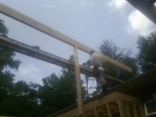 Carpenter setting a ridge beam over a new addition frame — Ice Dam Removal by Roofing Brothers in Kremlin