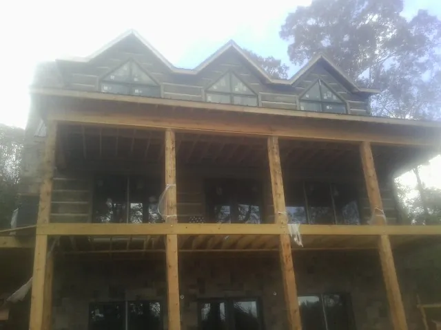 Dormers and porch framing on a large log home under construction — Roof Coating work by our crew in Kremlin