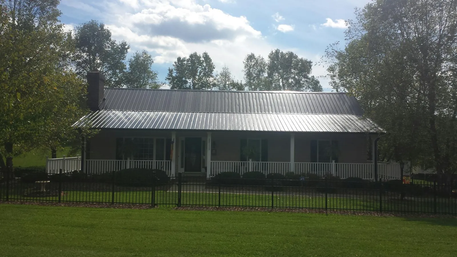 Gray metal roof on a brick ranch with a full width front porch in Kremlin