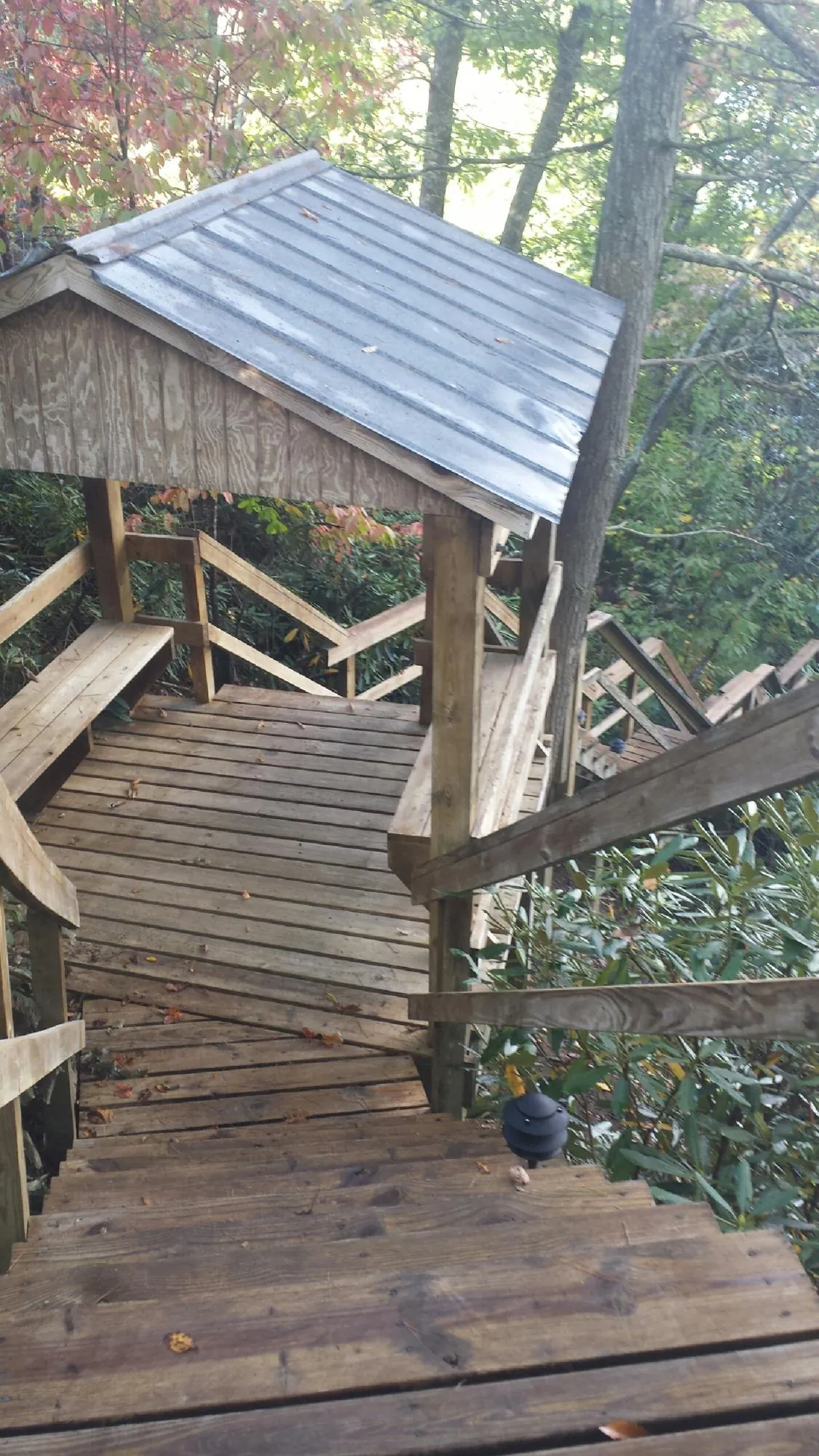 Metal roofed shelter over wooden steps on a wooded walkway — Skylight Repair & Installation work by our crew in Kremlin