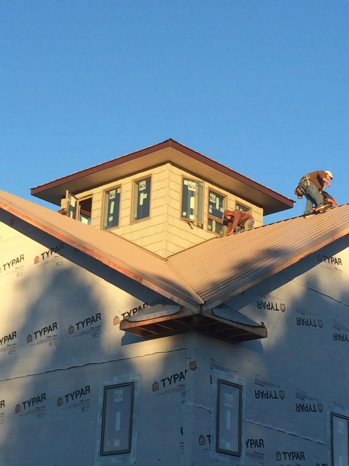 Roofers working around a rooftop cupola on a new metal roof at sunset — Roof Waterproofing in Kremlin by Roofing Brothers